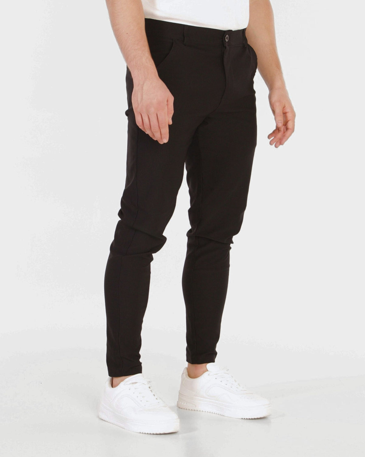 Grant Oak Smart Fit Chinos 4-Pack Essentials — person wearing black chinos and white sneakers on a white background.