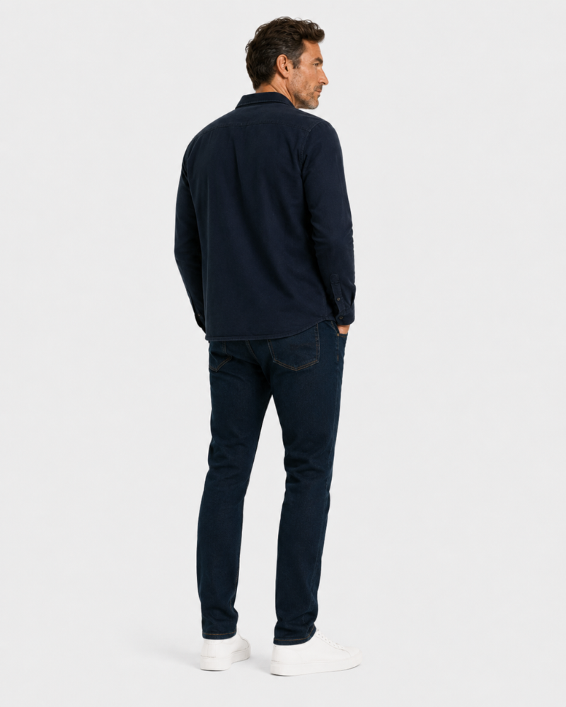 Man wearing a Grant Oak navy long-sleeve shirt and dark jeans on a white background #color_navy