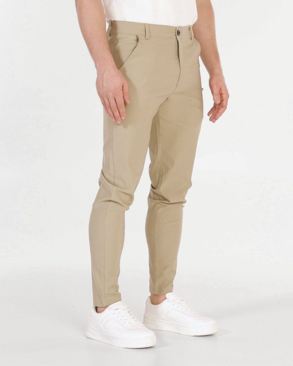 Grant Oak Smart Fit Chinos 4-Pack Essentials — slim-fit beige chinos with a white t-shirt and white sneakers, shown from the waist down against a light gray studio background.