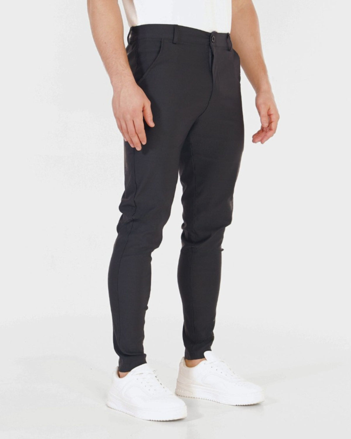 Grant Oak Smart Fit Chinos 4-Pack Essentials — person wearing dark charcoal gray chinos and white sneakers on a white background.