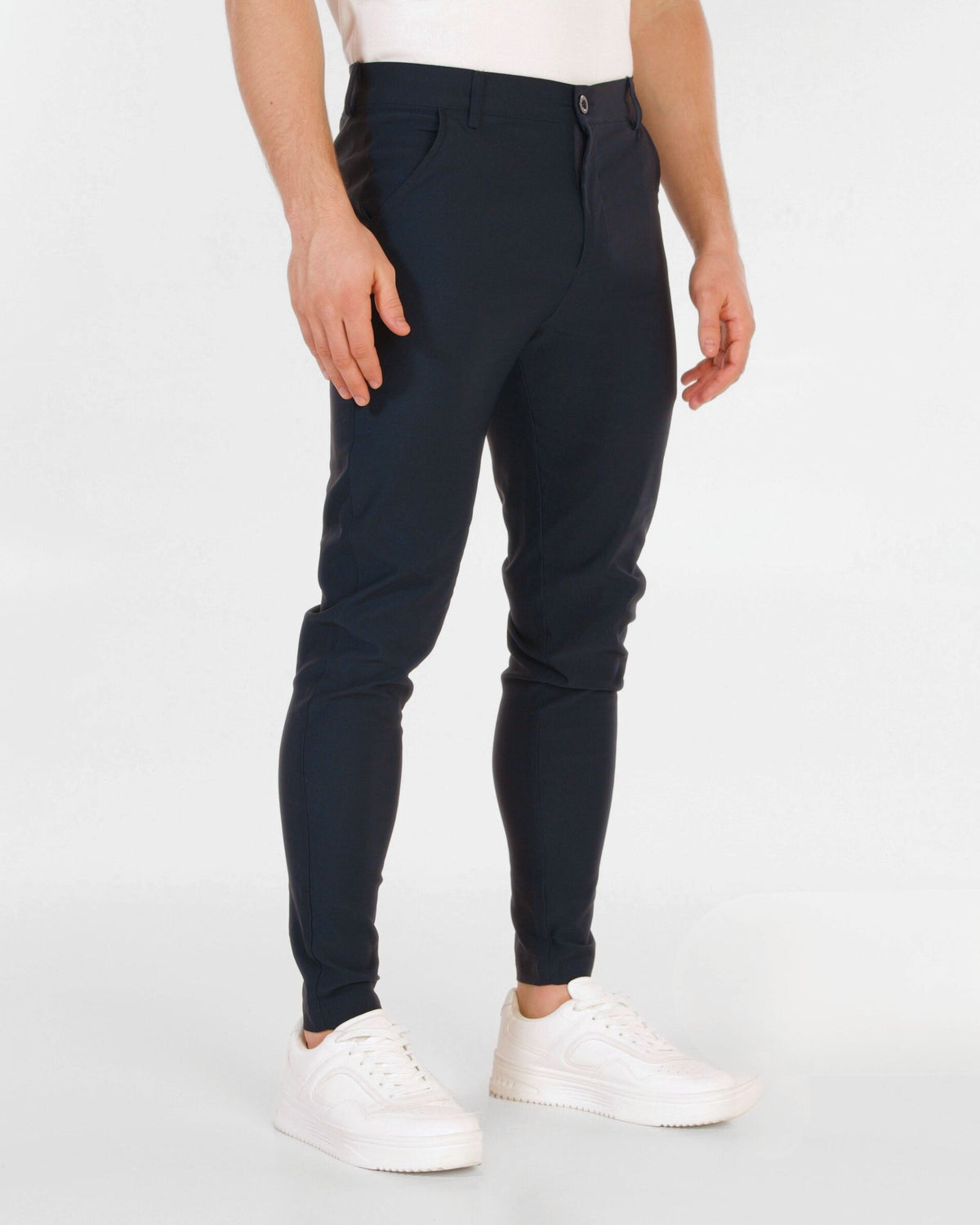 Grant Oak Smart Fit Chinos 4-Pack Essentials — person wearing navy chinos and white sneakers on a light gray background.