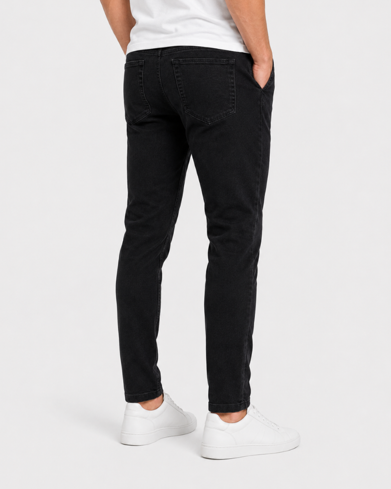 Grant Oak black slim fit jeans worn by a male model, cropped back angle view, light grey background #Color_black